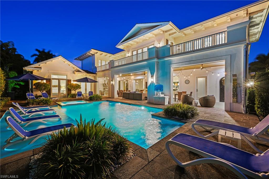 215 3rd Avenue North Naples, FL 34102 - Photo 42 of 47 Back of house at night with a balcony, french doors, an outdoor lounge area, a patio area, and stucco siding