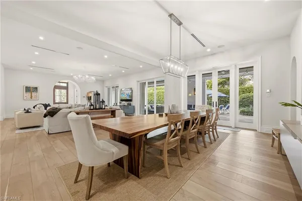 a dining room with wooden floor a chandelier a wooden table and chairs