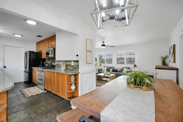 a large kitchen with stainless steel appliances kitchen island granite countertop a table and chairs in it