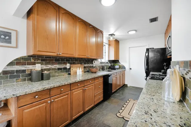 a kitchen with stainless steel appliances granite countertop a sink a stove and a refrigerator