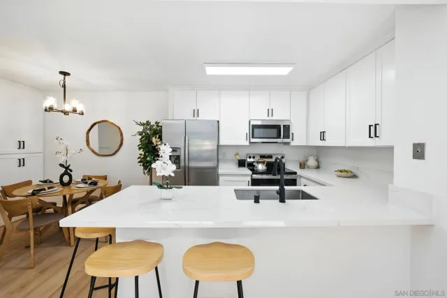 a kitchen with stainless steel appliances granite countertop a sink a stove a dining table and chairs