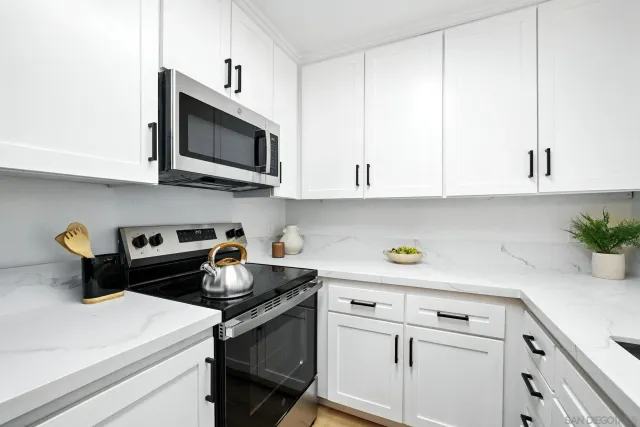 a kitchen with white cabinets and appliances
