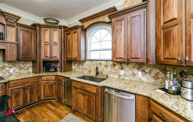 a kitchen with stainless steel appliances granite countertop a sink a stove and a wooden cabinets