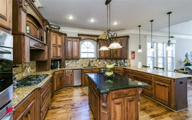 a kitchen with stainless steel appliances granite countertop a sink a stove and a wooden floors