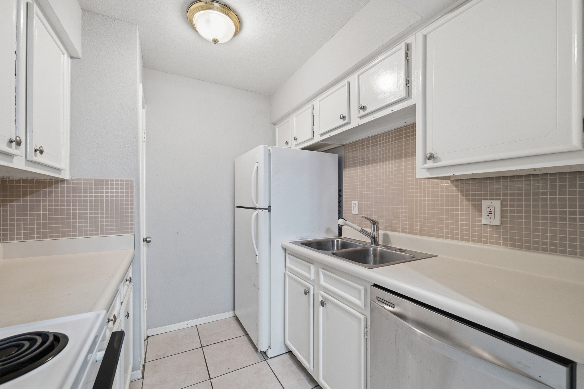 11550 Chimney Rock Road, Unit 133 Houston, TX 77035 - Photo 15 of 40 Cozy kitchen with modern white cabinetry, a dual sink, and a compact layout. The space features a tiled backsplash and ample countertop area, complemented by essential appliances for convenience.