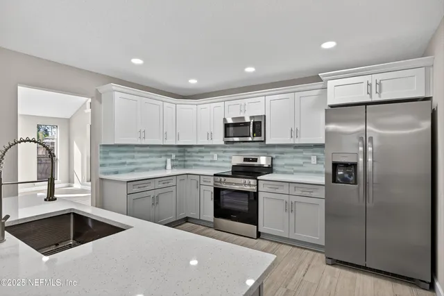 a kitchen with a sink stainless steel appliances and white cabinets