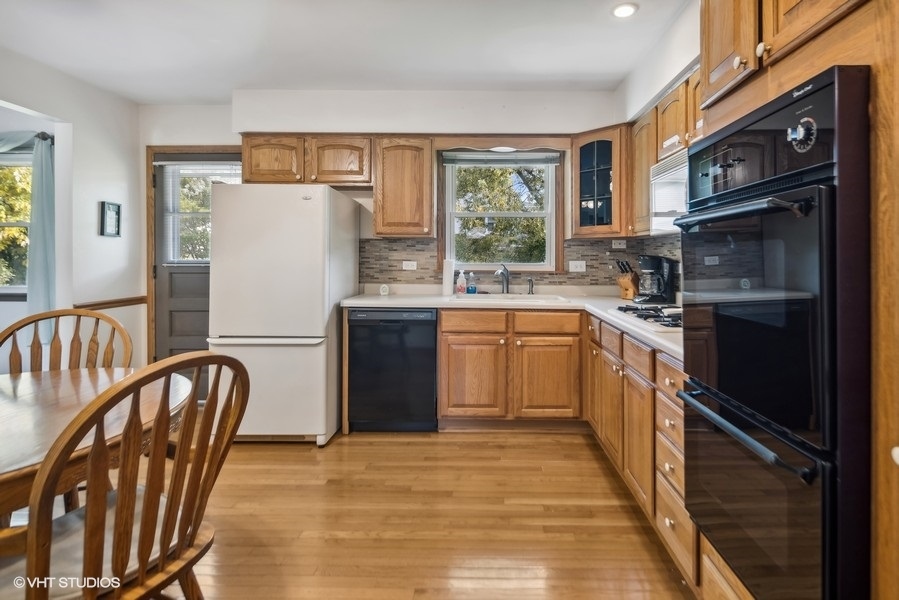 7631 Apple Tree Lane Willowbrook, IL 60527 - Photo 13 of 24 a kitchen with stainless steel appliances granite countertop a refrigerator a stove a sink a dining table and chairs with wooden floor