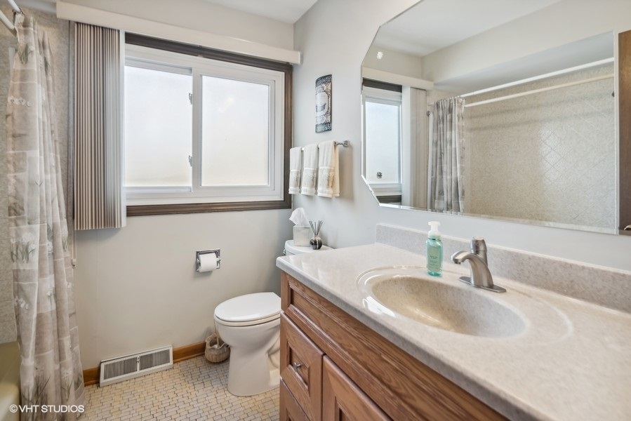 7631 Apple Tree Lane Willowbrook, IL 60527 - Photo 7 of 24 a bathroom with a sink a toilet and a mirror