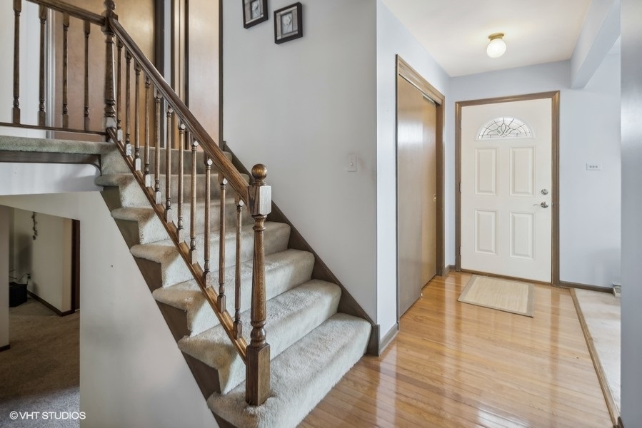 7631 Apple Tree Lane Willowbrook, IL 60527 - Photo 8 of 24 a view of staircase with lots of frames on wall and wooden floor