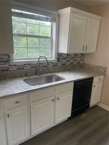a kitchen with granite countertop white cabinets white appliances and a sink