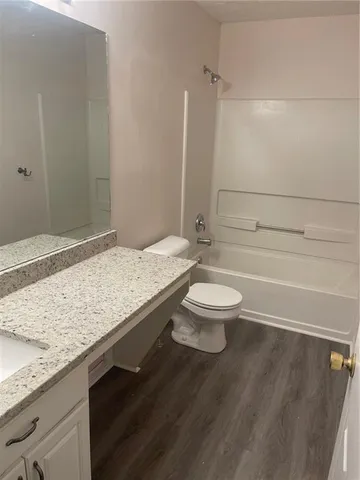 a bathroom with a granite countertop sink a toilet a mirror and bathtub