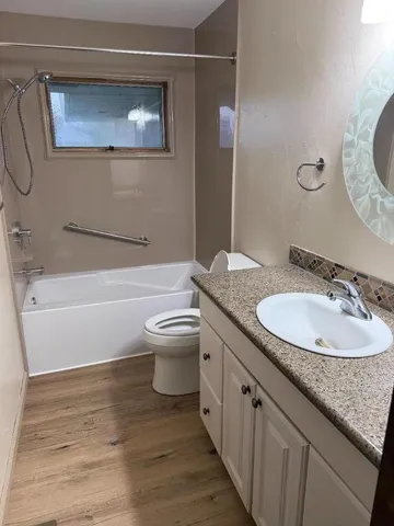 a bathroom with a granite countertop sink toilet and a mirror