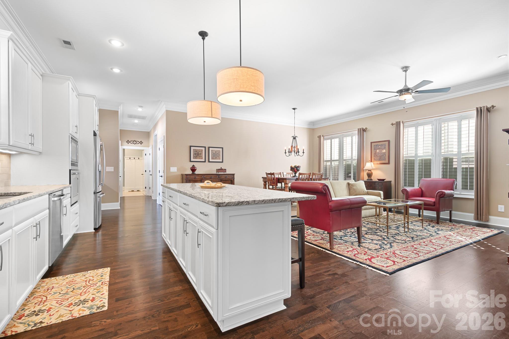 1215 Inn Keepers Way Cornelius, NC 28031 - Photo 34 of 35 a large kitchen with kitchen island granite countertop a stove a sink a refrigerator a dining table and chairs with wooden floor