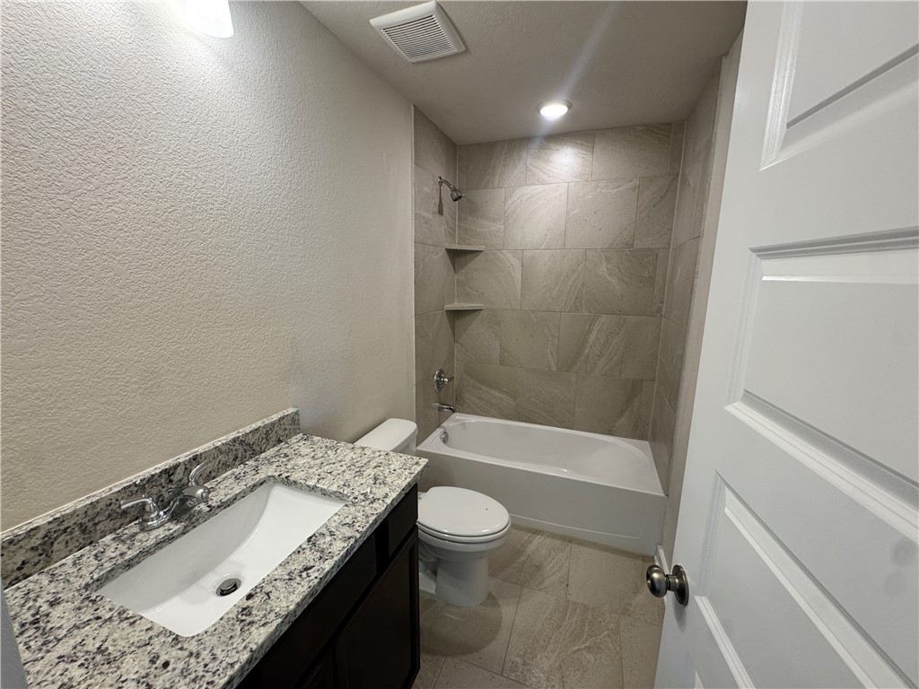2414 Rooke Road Bryan, TX 77807 - Photo 7 of 11 a bathroom with a granite countertop sink a toilet and bathtub