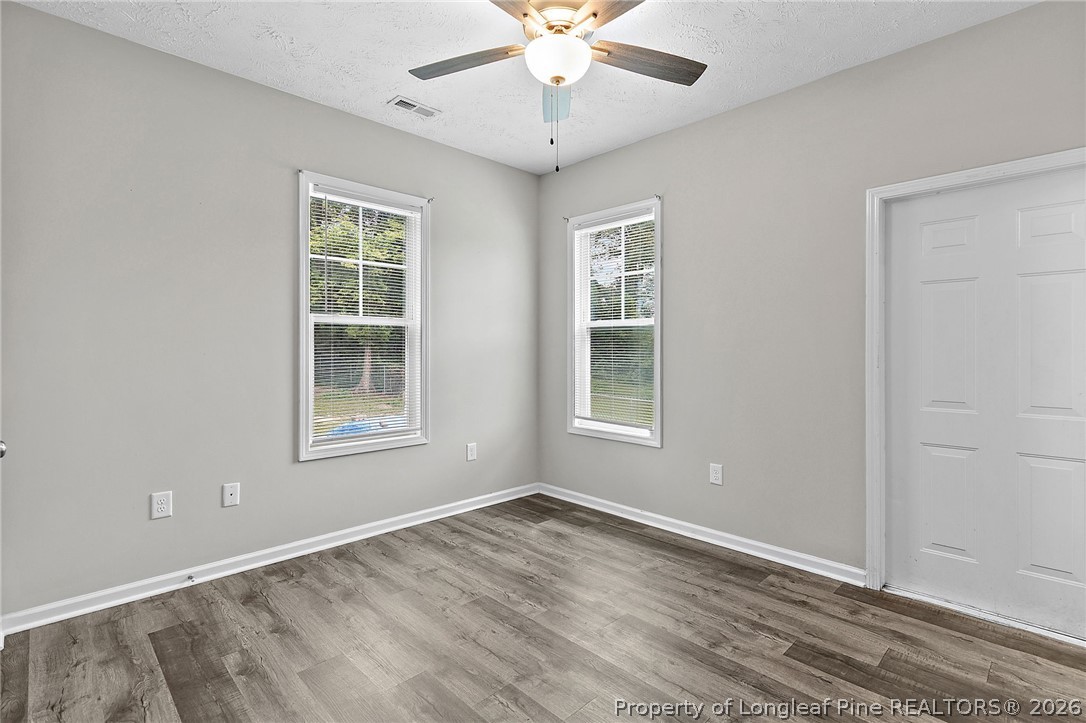 215 Old Wilmington Road Fayetteville, NC 28301 - Photo 14 of 31 an empty room with wooden floor chandelier fan and windows