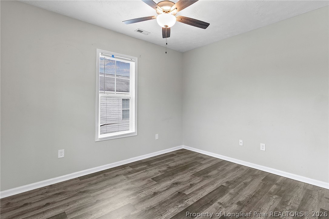 215 Old Wilmington Road Fayetteville, NC 28301 - Photo 4 of 31 an empty room with wooden floor chandelier fan and windows