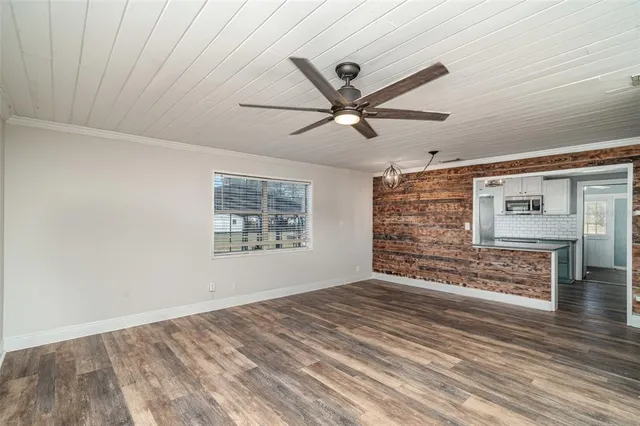 a view of an empty room with window and a ceiling fan