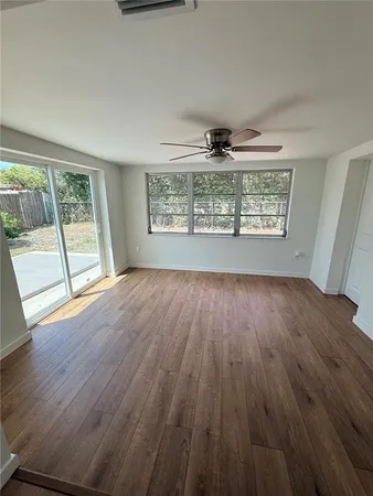 a view of an empty room with wooden floor and a window