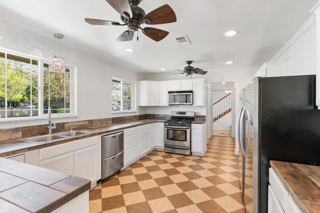 a open kitchen with stainless steel appliances granite countertop a sink a stove a refrigerator cabinets and dining table