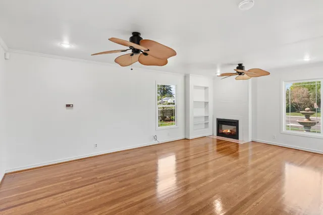 a view of a livingroom with a fireplace a ceiling fan and window