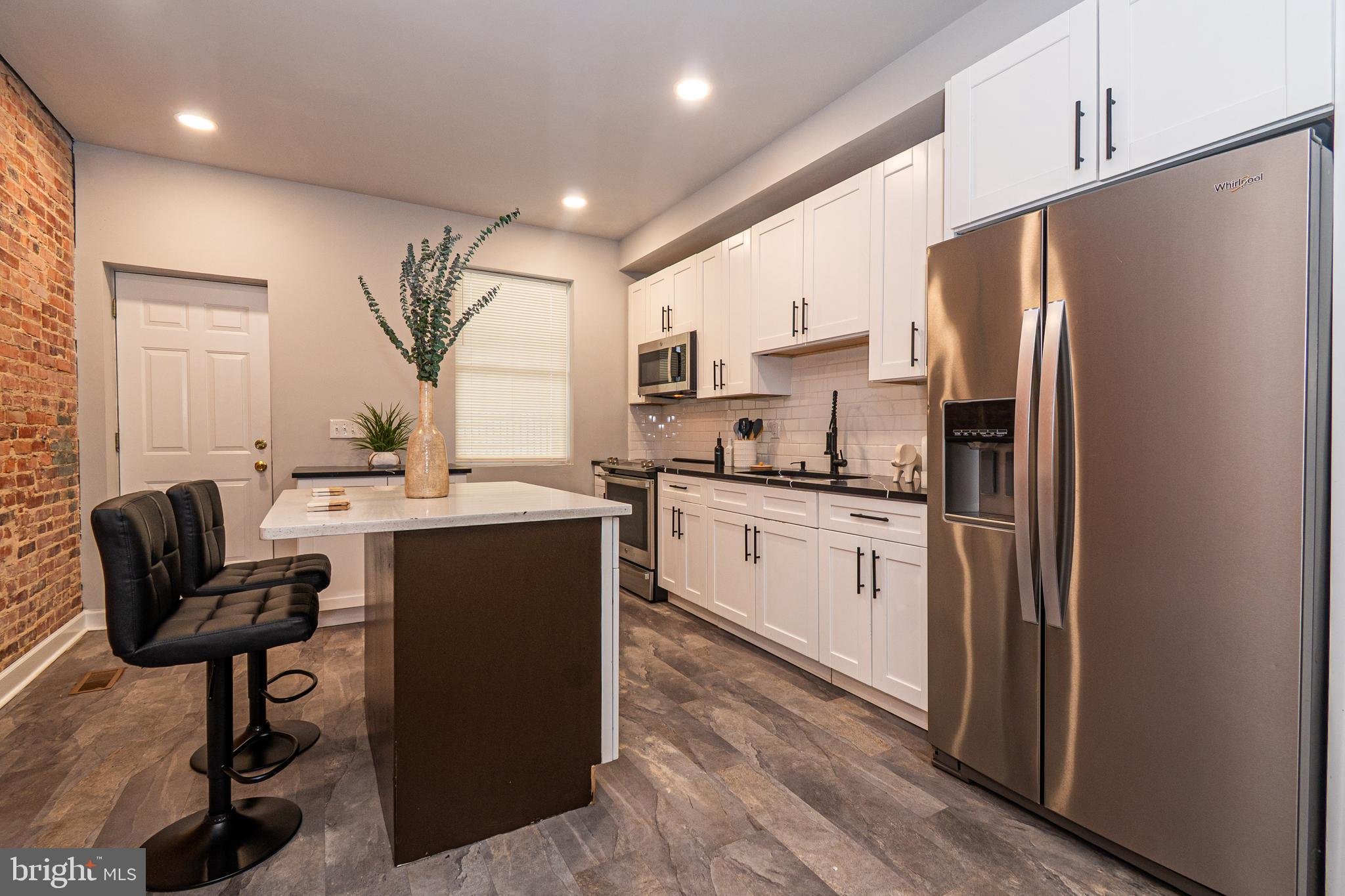 3103 East Monument Street Baltimore, MD 21205 - Photo 6 of 20 a kitchen with a refrigerator a sink and chairs