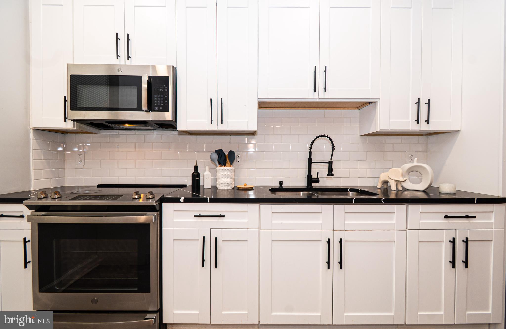 3103 East Monument Street Baltimore, MD 21205 - Photo 7 of 20 a kitchen with granite countertop white cabinets and stainless steel appliances