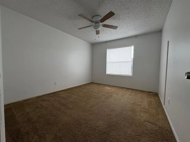 an empty room with windows and ceiling fan
