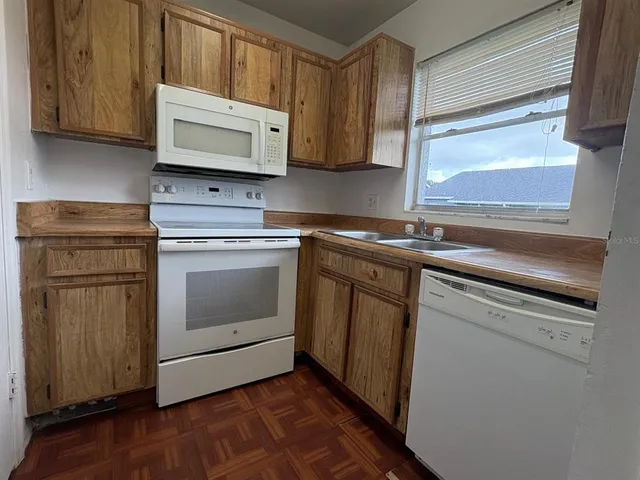 a kitchen with granite countertop white cabinets appliances and wooden floor