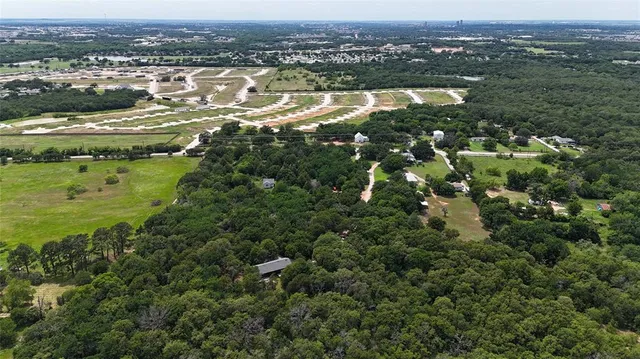 an aerial view of residential houses with outdoor space and trees