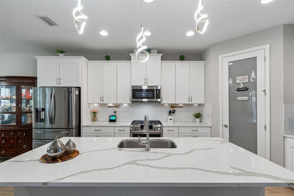 4300 Burdick Loop Odessa, FL 33556 - Photo 9 of 41 a kitchen with stainless steel appliances kitchen island granite countertop a refrigerator a stove a sink and white cabinets with wooden floor