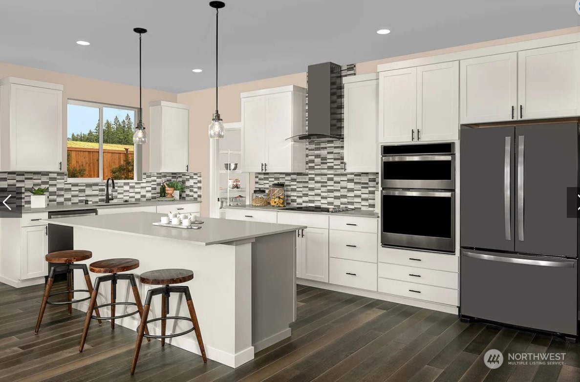 3545 Edith Avenue, Unit 28 Enumclaw, WA 98022 - Photo 3 of 10 a kitchen with stainless steel appliances kitchen island granite countertop a refrigerator a stove a sink and white cabinets with wooden floor