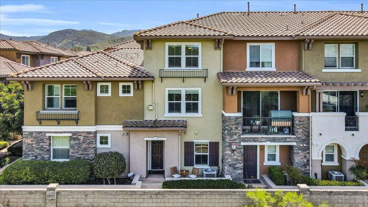 a front view of a residential apartment building with a yard and potted plants