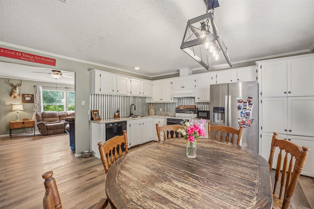 151 High Point Road Weatherford, TX 76088 - Photo 11 of 40 a kitchen with stainless steel appliances kitchen island granite countertop a table chairs in it and a wooden floors