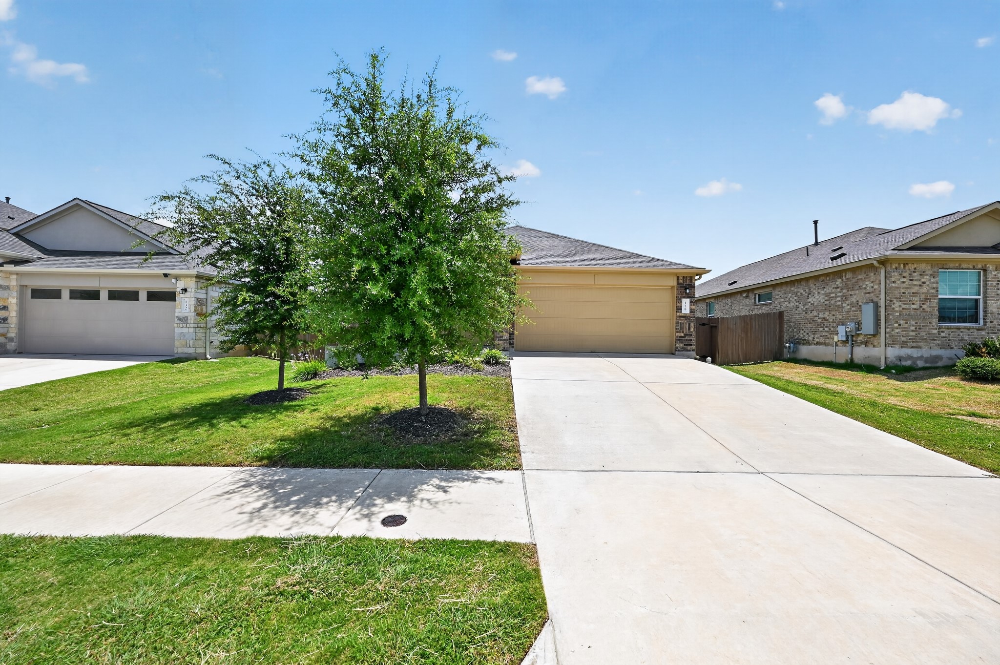 128 Konik Road Georgetown, TX 78626 - Photo 2 of 34 A welcoming front exterior showcasing mature trees, a well-maintained lawn, and a spacious driveway.