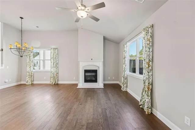 a kitchen with granite countertop a refrigerator a sink dishwasher a stove and white cabinets with wooden floor