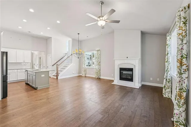 a kitchen with stainless steel appliances granite countertop a stove top oven a sink a refrigerator white cabinets and wooden floor