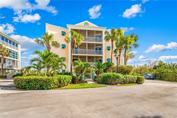 a front view of a multi story residential apartment building with yard and parking