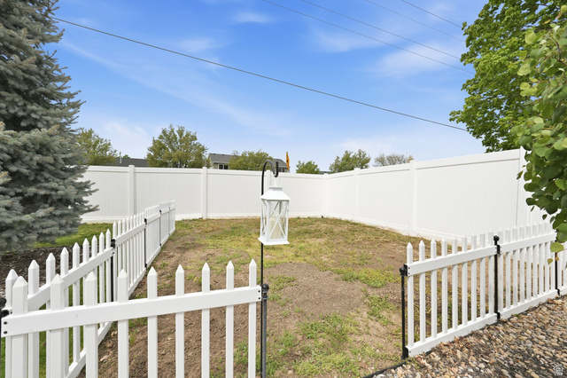 2190 West 1450th Street North Layton, UT 84041 - Photo 5 of 11 Enclosed backyard featuring a white privacy fence, an interior white picket fence, and mature perimeter trees
