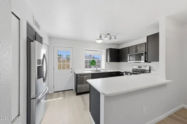 a kitchen with a refrigerator a sink and dishwasher with white cabinets
