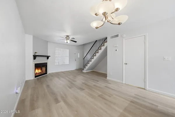 a view of an empty room with wooden floor fireplace and a window