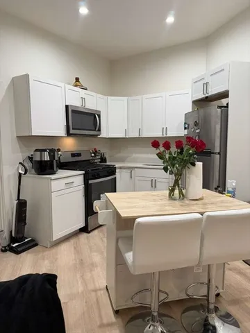 a kitchen with stainless steel appliances kitchen island granite countertop a sink dishwasher a stove a refrigerator a microwave oven with cabinets and wooden floor