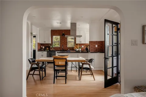 a kitchen with stainless steel appliances kitchen island granite countertop a table chairs and a refrigerator