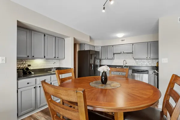 a kitchen with a dining table chairs and refrigerator