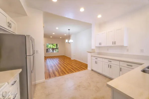 a kitchen with a refrigerator sink and white cabinets with wooden floor