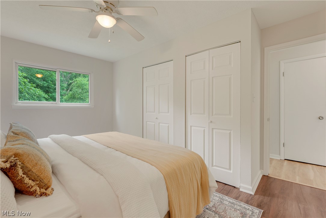 646 Ledge Road Macedonia, OH 44056 - Photo 13 of 28 Bright room featuring a ceiling fan with integrated lighting, two bi-fold panel doors, wood-finish flooring, and a window framing mature trees