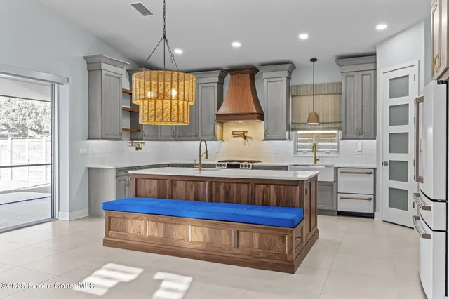 a large white kitchen with kitchen island a large counter space a sink stainless steel appliances and cabinets