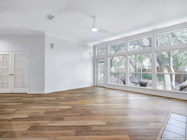a view of an empty room with wooden floor and a window