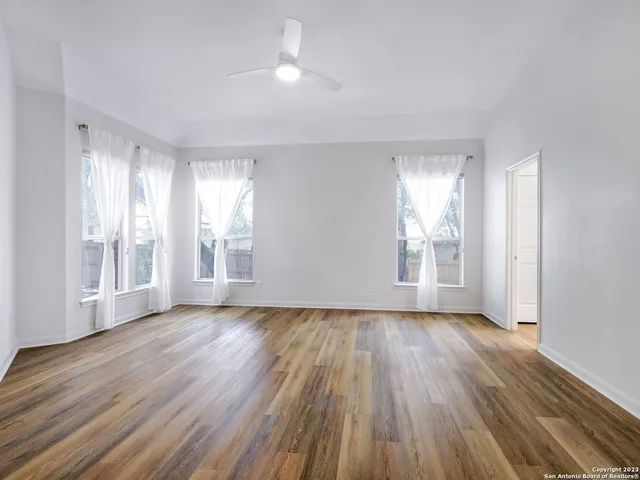 a view of an empty room with wooden floor and a window