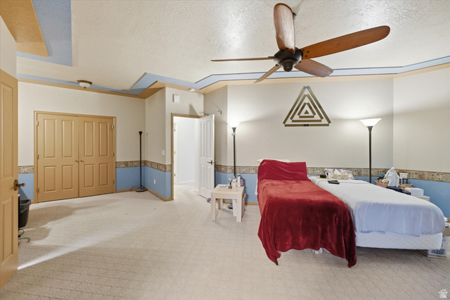 560 East 700 North Logan, UT 84321 - Photo 9 of 32 Spacious room featuring neutral carpeting, a tray ceiling with accent molding, a ceiling fan, and double bi-fold doors