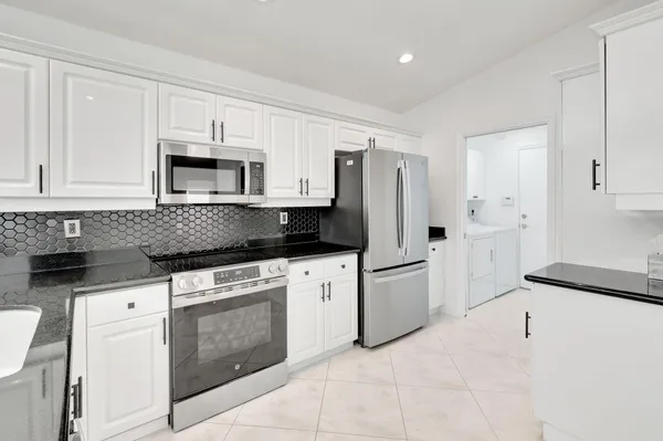 a kitchen with granite countertop white cabinets and black appliances